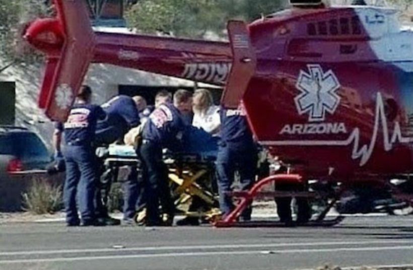Gabby Giffords on a stretcher with emergency medical personnel on the site following the shooting